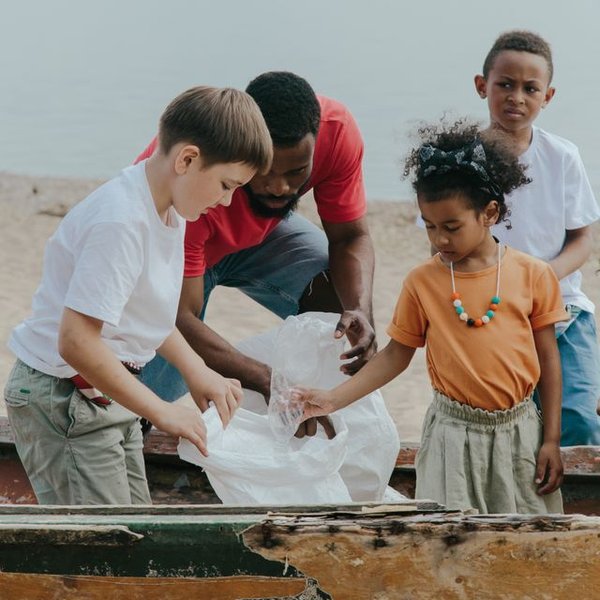 A man and children picking up litter on the beach